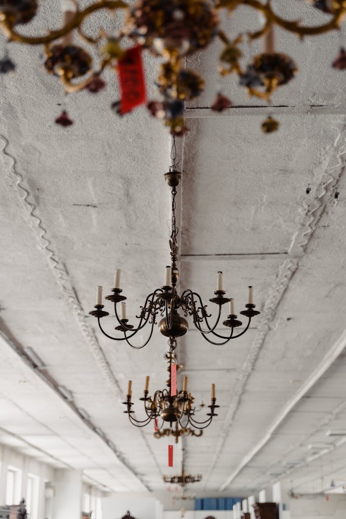 Elegant vintage chandeliers hanging from the ceiling in an antique shop setting.